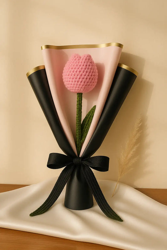 Pink crocheted tulip in a black and gold holder on a beige background