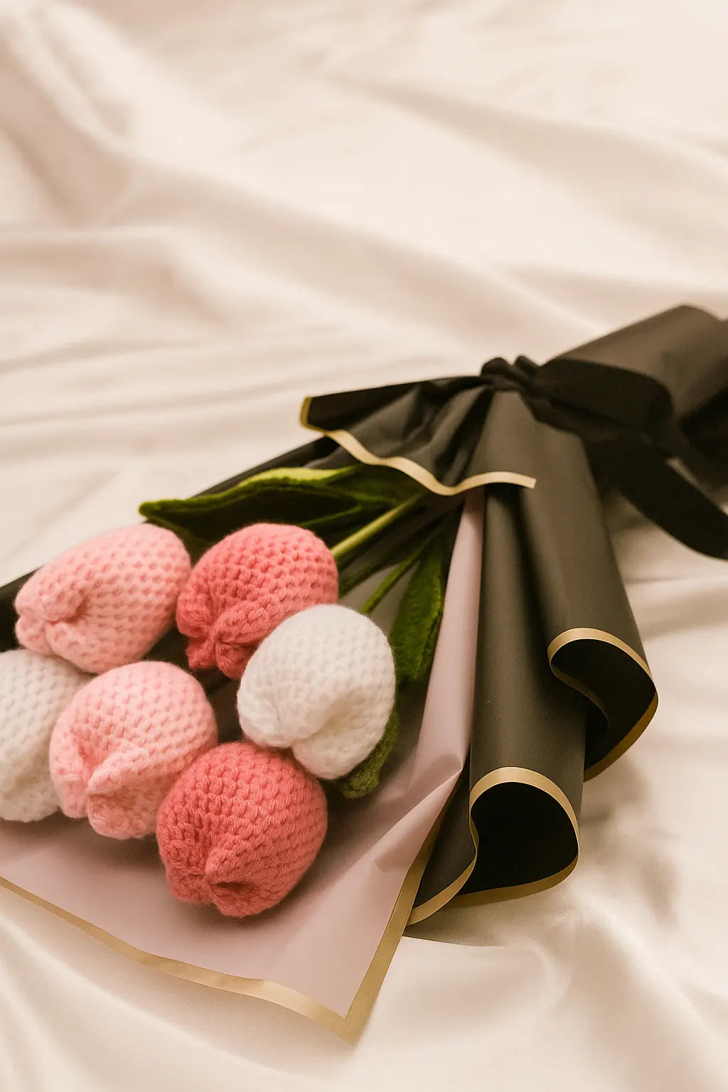 Knitted flowers in pink, white, and green on a white background
